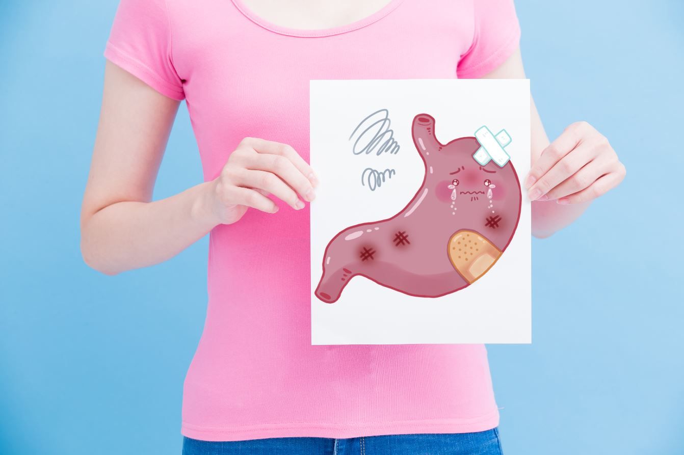 Woman holding an illustration of a sad cartoon stomach