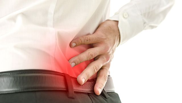 Hand holding lower back in pain