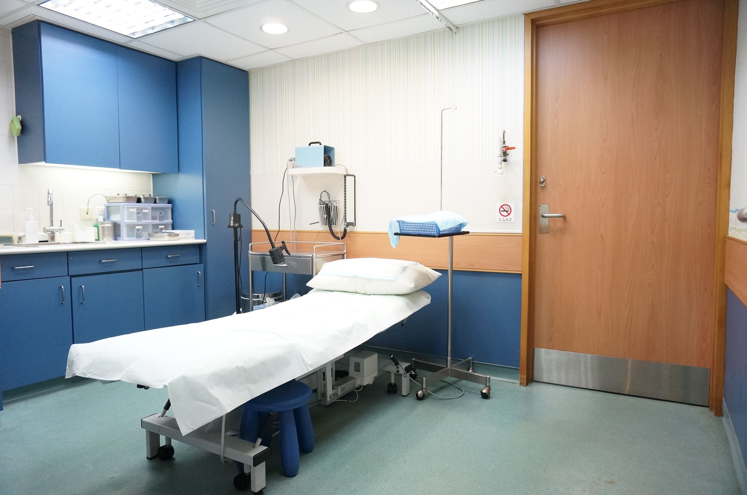 Examination room with patient bed and blue cabinets