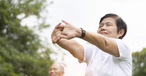 Older woman outdoors stretching arms forward