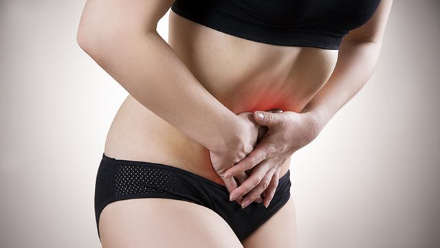 Woman with both hands on painful abdomen