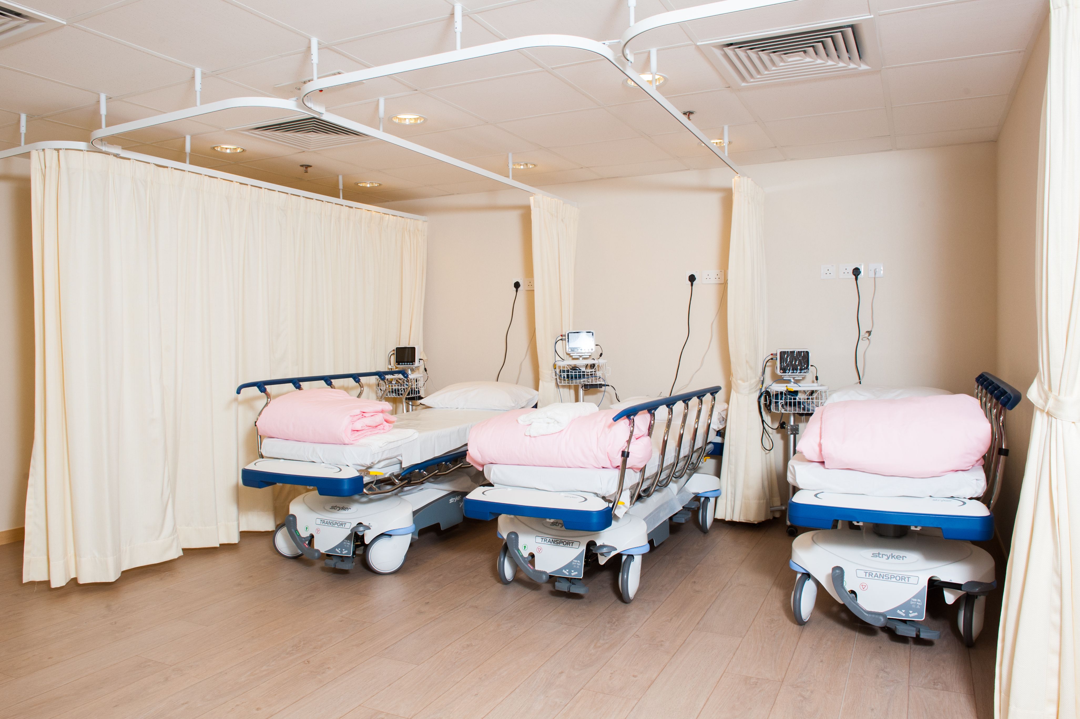 Three patient beds in a large room that can be divided with curtains