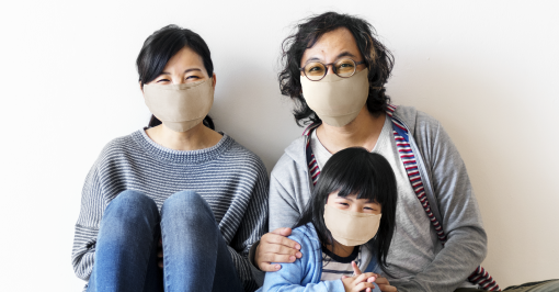 Two adults and a young girl sitting down wearing face masks