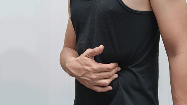 Man pressing left abdomen with right hand