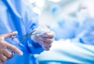 Close-up of a doctor using surgical scissors to cut gauze in an operating room