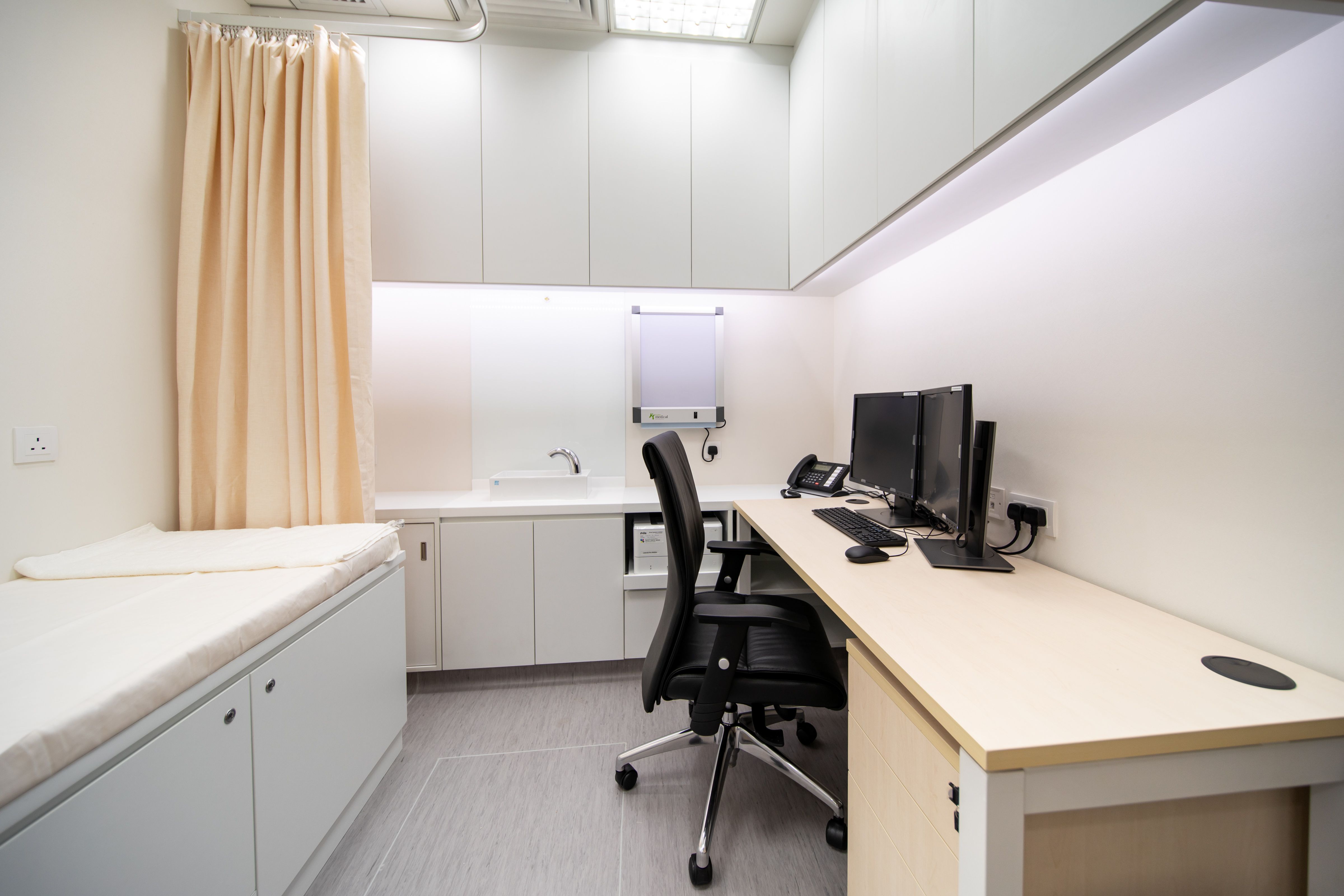 Examination room with patient bed, curtain, desk