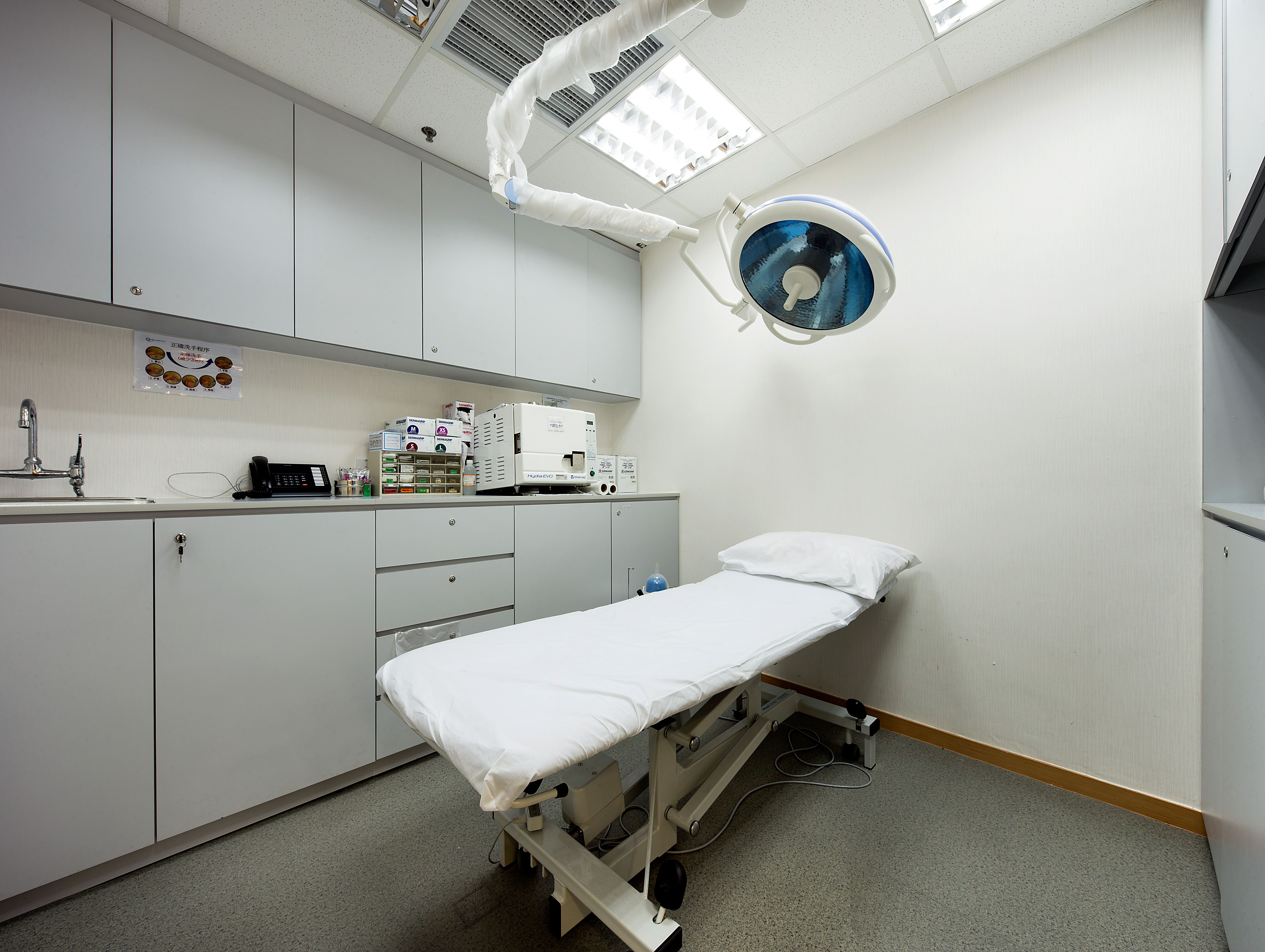 Examination room with patient bed, overhead light and cabinets
