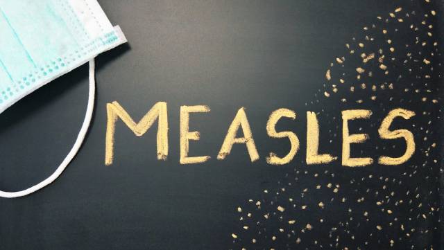 Surgical mask and the word Measles written in gold on black background