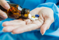 Close-up of a doctor pouring pills from a bottle into their hand