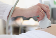 Close-up of a hand performing an ultrasound on a patient's abdomen