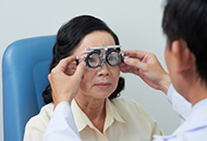 An optometrist holding test lenses on a female patient's eyes