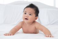 Naked baby lying on its stomach with head raised