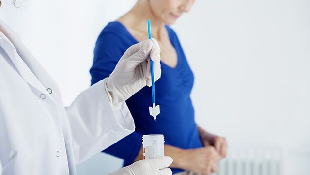 Doctor inserting a pap smear swab into a plastic tube