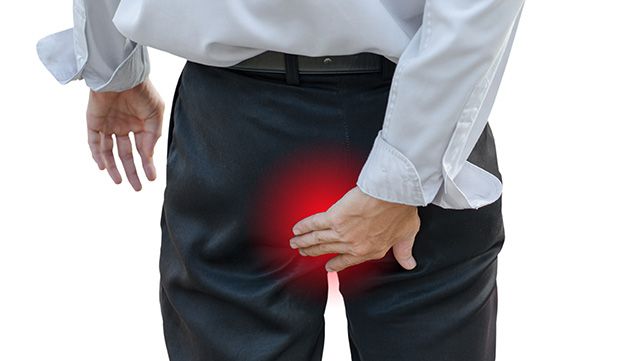 Man holding his hand over the area of his rectum and painful piles