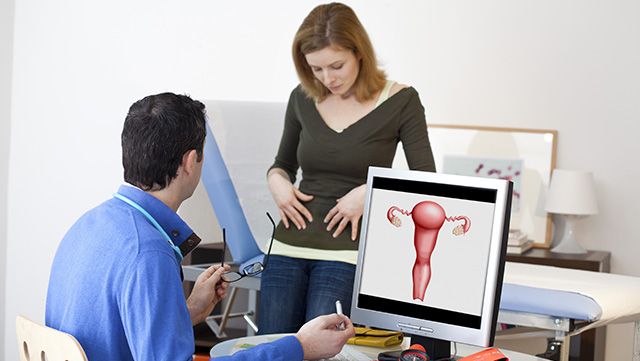 Female patient pointing at her abdomen as doctor explains polycystic ovarian syndrome