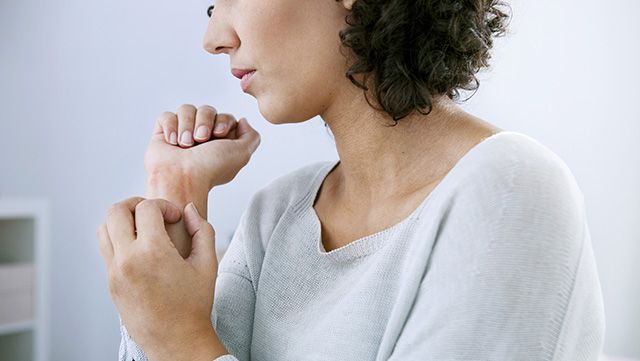 Woman scratching irritated skin on her wrist