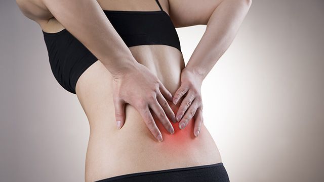 Woman with both hands placed on sore lower back