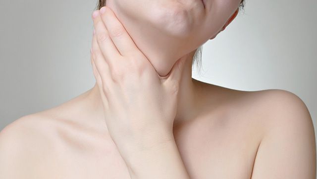 Close-up of a woman holding her throat and tilting her head sideways