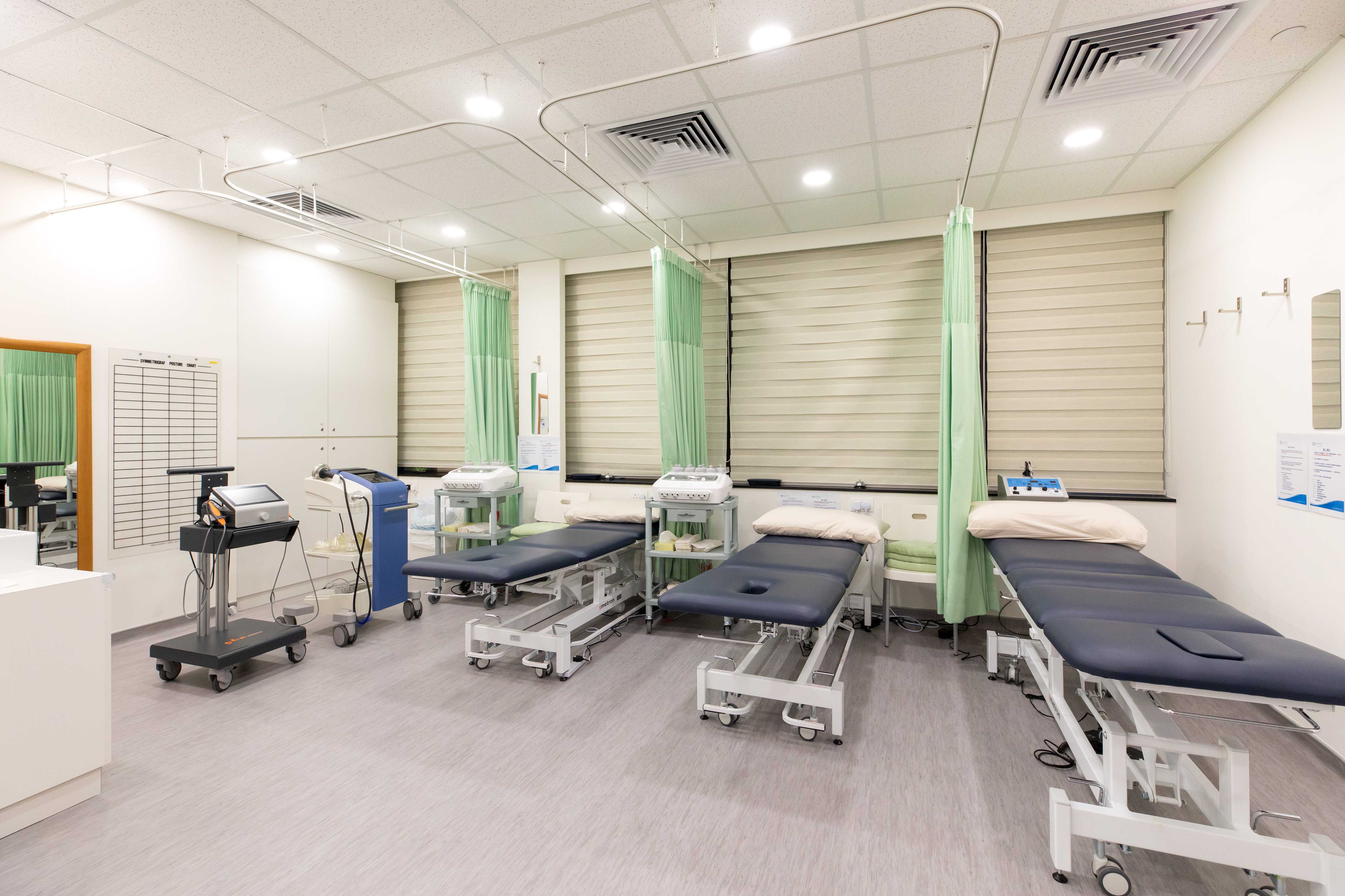 Three physiotherapy beds in a large room that can be divided with curtains
