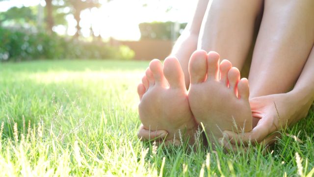 Bare feet and legs of a person sitting in the grass