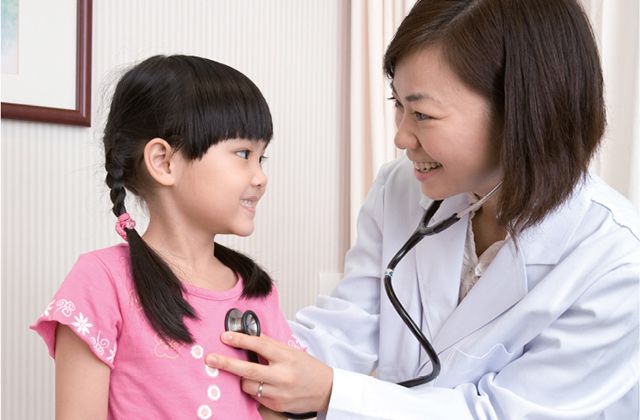 Female doctor using stethoscope to listen to young girl's heart
