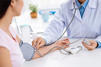 Doctor taking woman's blood pressure