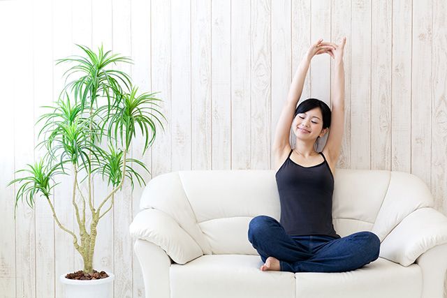 Woman sitting on a sofa and stretching