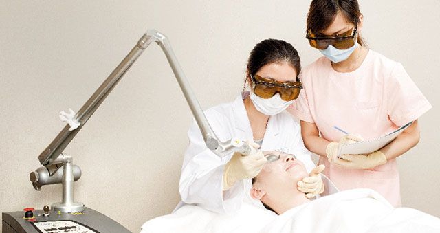 Doctor and nurse performing a medical aesthetics procedure with laser