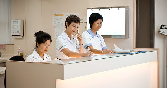 Three staff members at medical centre reception desk