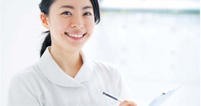Smiling nurse holding a clipboard and writing on it
