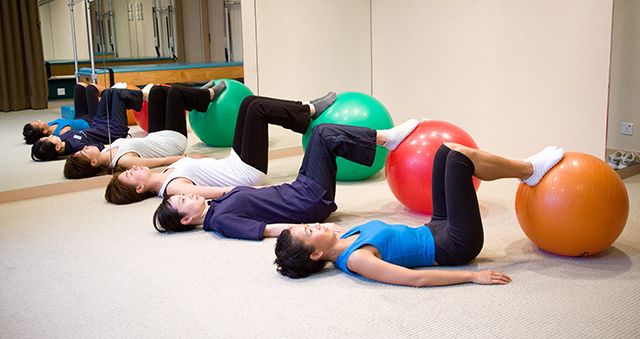 Three women lying down resting their feet on exercise balls