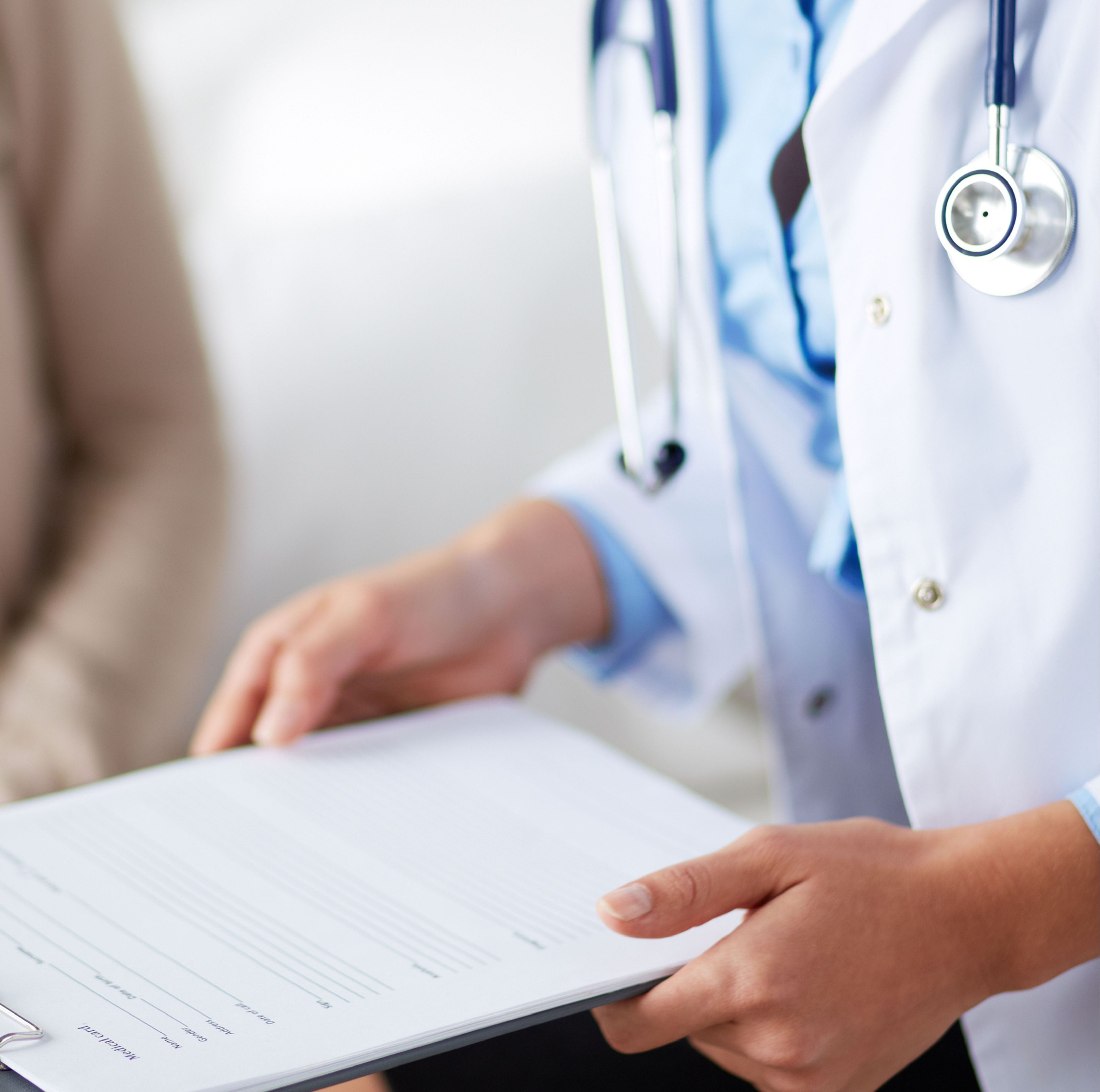 Close-up of doctor's hands writing on a patient chart