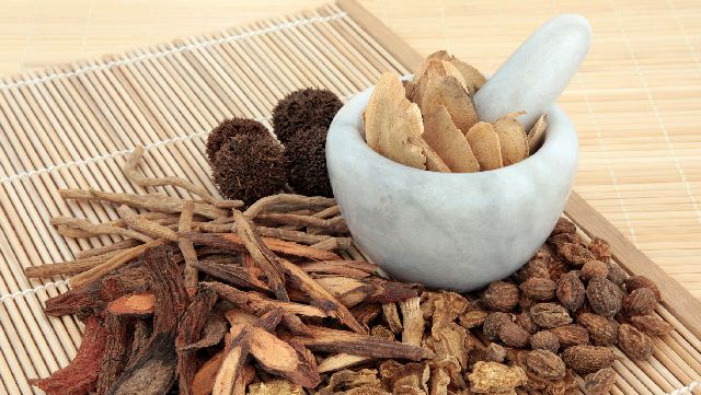 Chinese medicine herbs and mortar and pestle on a wooden mat
