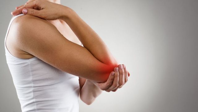 Close-up of woman holding painful right elbow with left hand