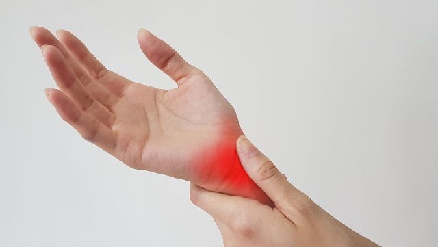 Close-up of woman holding painful right wrist with left hand